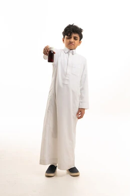 طفل سعودي بالثوب يحمل زجاجة دواء بتعبير اشمئزاز