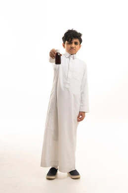 طفل سعودي بالثوب التقليدي يحمل زجاجة دواء عابساً