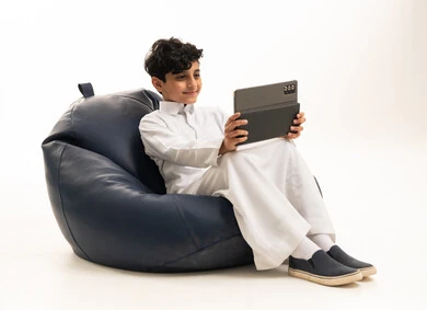 Saudi Boy in Thobe Using Tablet on Bean Bag