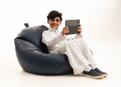 Saudi Boy in White Thobe Holding Tablet on Bean Bag