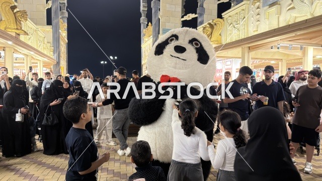 دمية باندا وحشود في القرية العالمية بدبي ليلاً