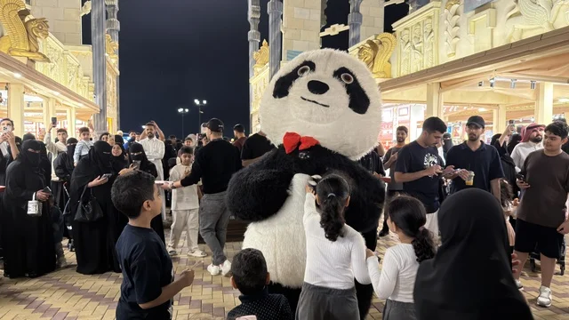 دمية باندا وحشود في القرية العالمية بدبي ليلاً