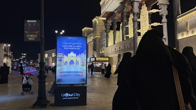 مشهد ليلي في القرية العالمية بدبي مع شاشة إعلانية