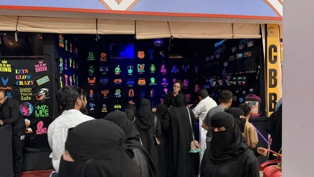 متجر لوحات نيون مع حشد بملابس تقليدية