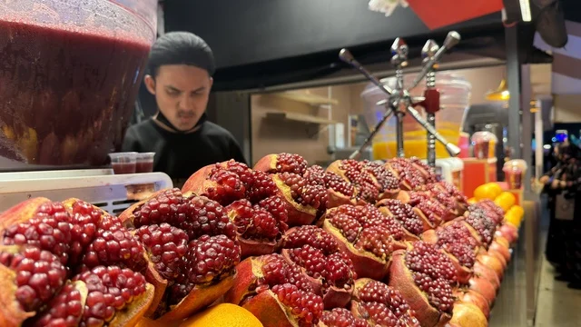 كشك عصير رمان طازج مع بائع متجول في السوق