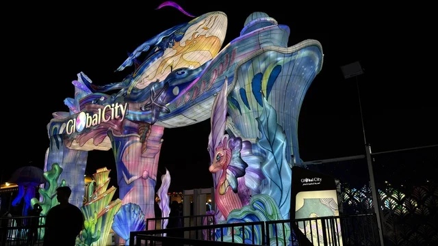 بوابة مدخل جلوبال سيتي المضيئة بطابع بحري ليلاً