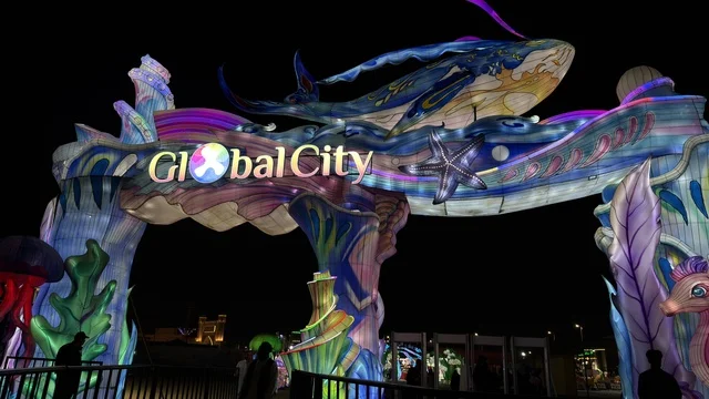 قوس مدخل جلوبال سيتي مع مجسم حوت مضيء ليلاً