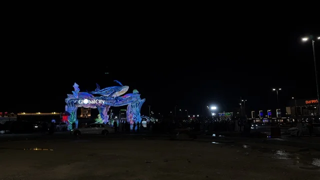 مدخل مدينة جلوبال سيتي مع حوت مضيء بأضواء نيون ليلاً