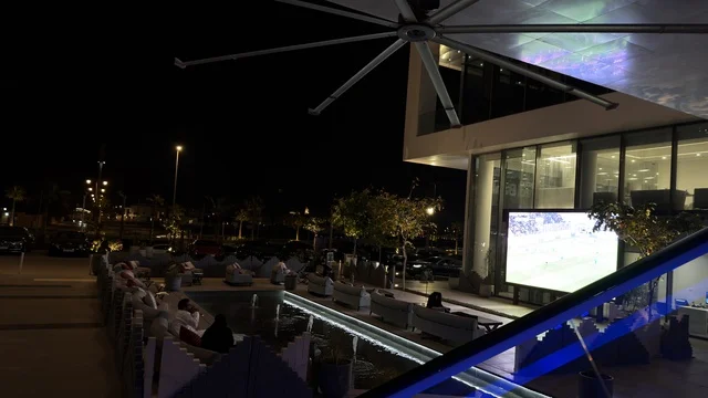 مشاهدة مباراة كرة قدم في مقهى خارجي حديث ليلاً