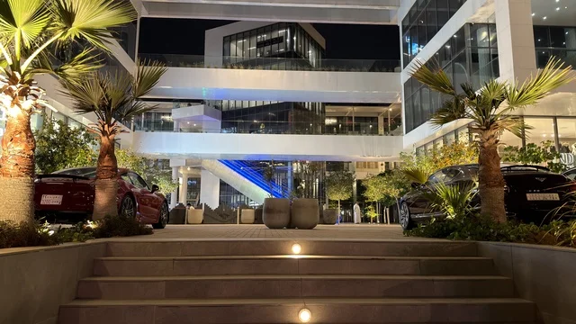 Modern Plaza Building and Luxury Sports Cars at Night