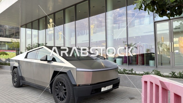 سيارة تسلا سايبرترك متوقفة أمام مبنى زجاجي حديث في وضح النهار