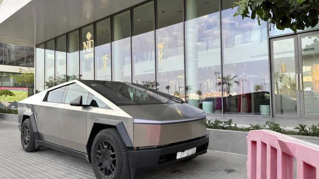 سيارة تسلا سايبرترك متوقفة أمام مبنى زجاجي حديث في وضح النهار
