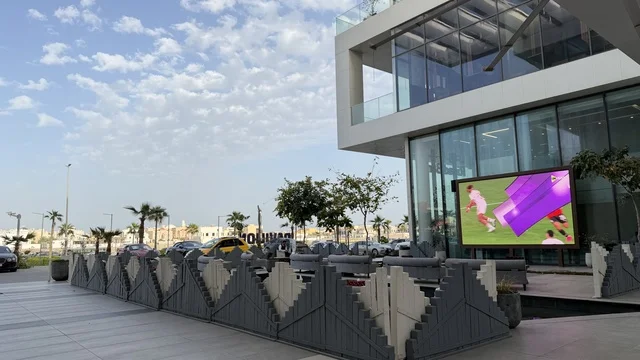 شاشة عرض خارجية تعرض مباراة كرة قدم أمام مبنى حديث