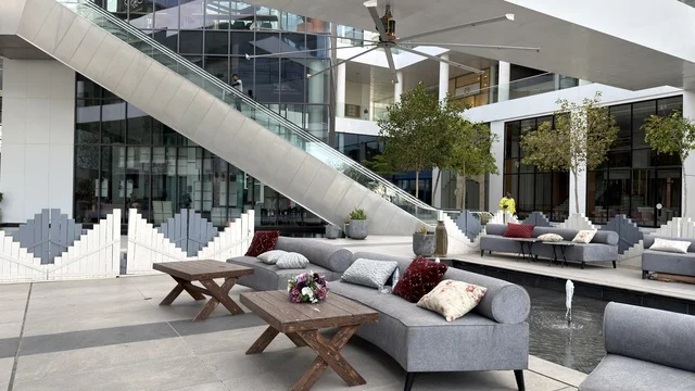 جلسة خارجية حديثة وسلم كهربائي في ساحة تجارية