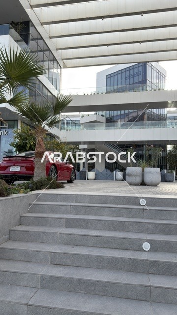 سيارة حمراء فاخرة أمام مجمع تجاري حديث بالرياض