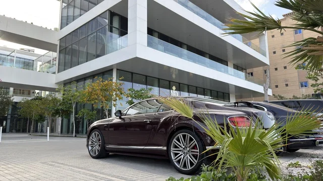 سيارة فاخرة متوقفة أمام مبنى إداري حديث