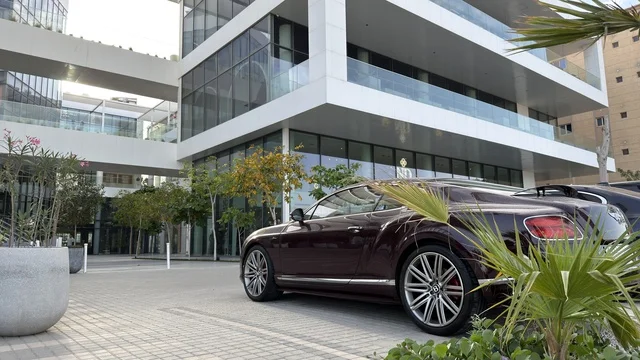 سيارة فاخرة أمام مبنى معماري حديث في وضح النهار