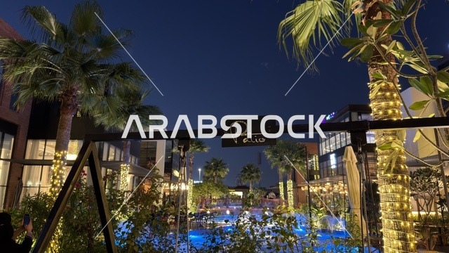 منطقة جلسات الباتيو الخارجية ليلاً مع النخيل المضيء