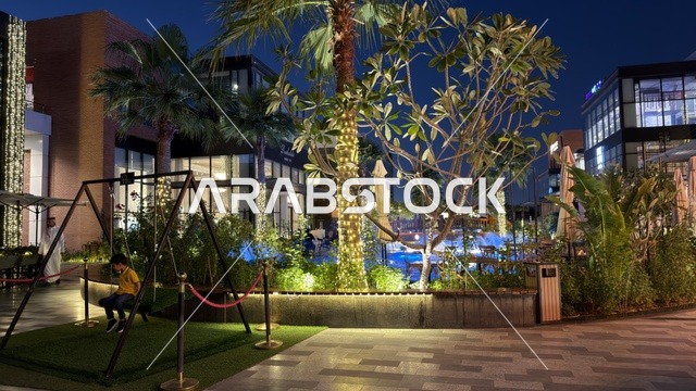 طفل على أرجوحة في ساحة تسوق ليلية