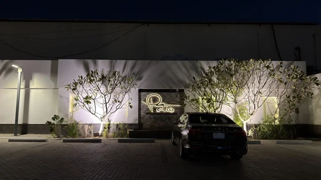 واجهة مبنى تجاري حديث مع لوحة نيون باتيو في الليل