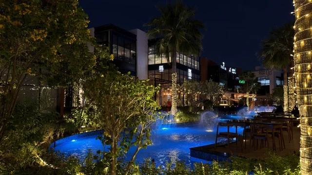 ساحة خارجية حديثة مع نافورة زرقاء مضاءة ليلاً