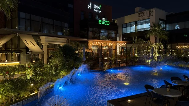 ساحة مطاعم حديثة مع نافورة مضيئة في الليل