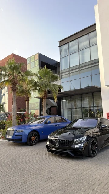 سيارات فاخرة متوقفة بجانب مبنى زجاجي حديث