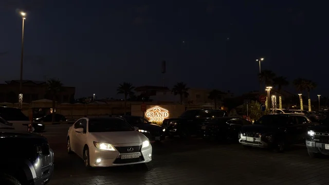 White Sedan in Night Parking Lot with Illuminated Sign