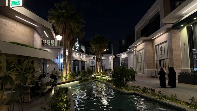 ساحة خارجية حديثة ليلاً مع مسطح مائي وإضاءة