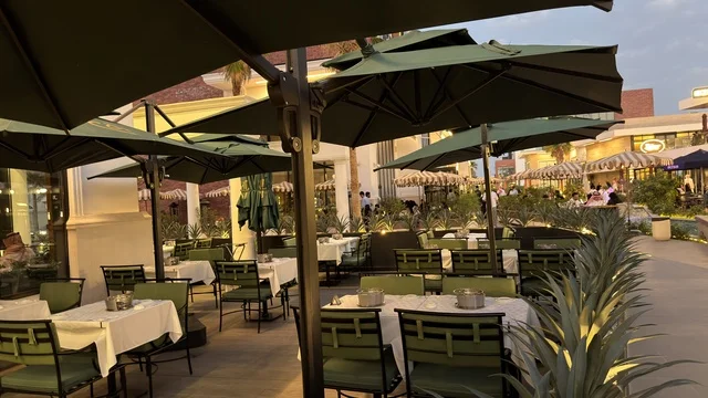 جلسات مطعم خارجية مع مظلات خضراء وقت الغسق