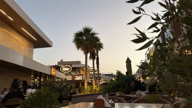 ساحة مطاعم خارجية مع أشجار النخيل عند الغروب