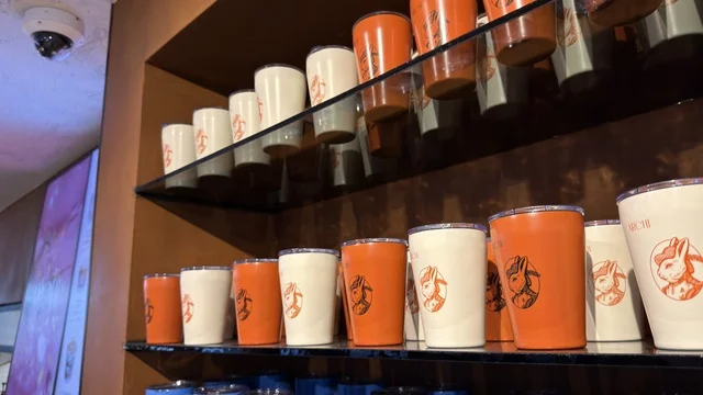 أكواب حرارية بعلامة تجارية على أرفف متجر تجزئة