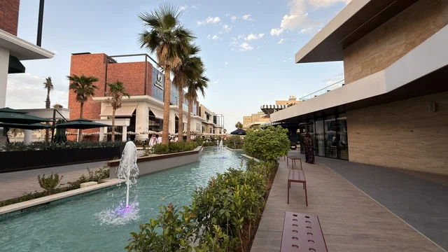 مجمع تسوق خارجي حديث مع نافورة مياه وأشجار نخيل