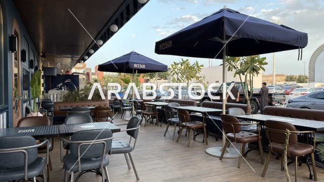 منطقة جلسات خارجية لمطعم مع مظلات زرقاء