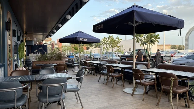 منطقة جلسات خارجية لمطعم مع مظلات زرقاء