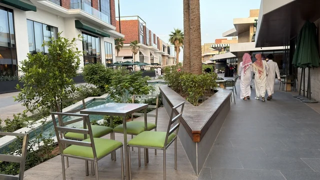 رجال سعوديون يتجولون في مجمع تجاري خارجي حديث بضوء النهار