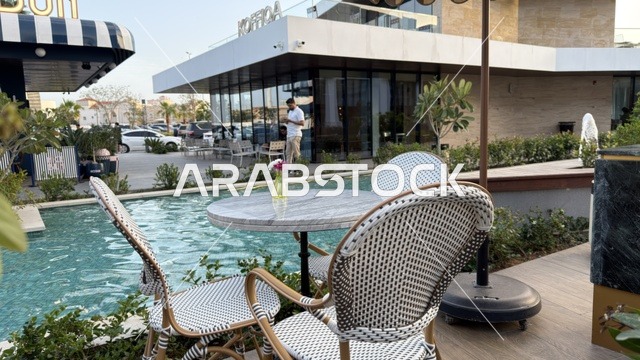 جلسة مطعم خارجية بجانب مسبح مع مباني تجارية حديثة