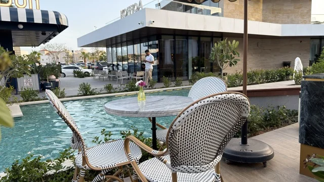 جلسة مطعم خارجية بجانب مسبح مع مباني تجارية حديثة
