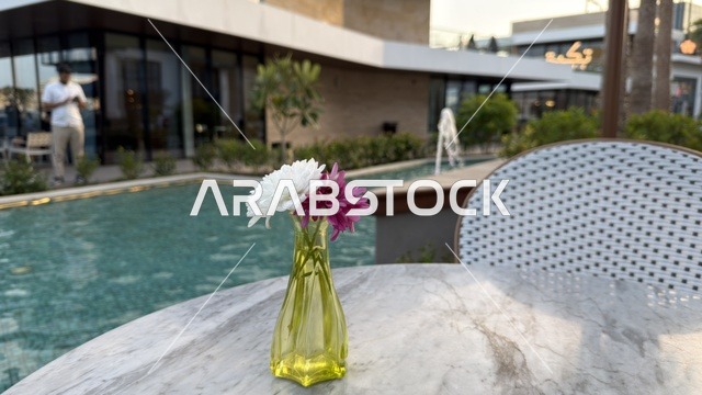 مزهرية زهور على طاولة رخامية في مقهى خارجي