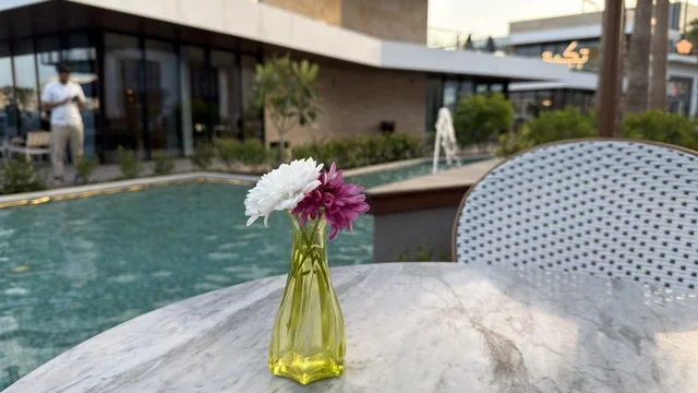 مزهرية زهور على طاولة رخامية في مقهى خارجي