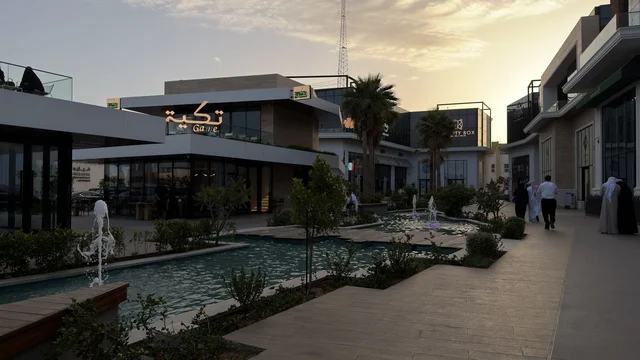 ساحة تسوق خارجية حديثة عند غروب الشمس مع نوافير