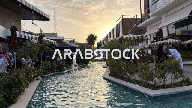 مجمع تجاري حديث مع قناة مائية ونافورة عند الغروب