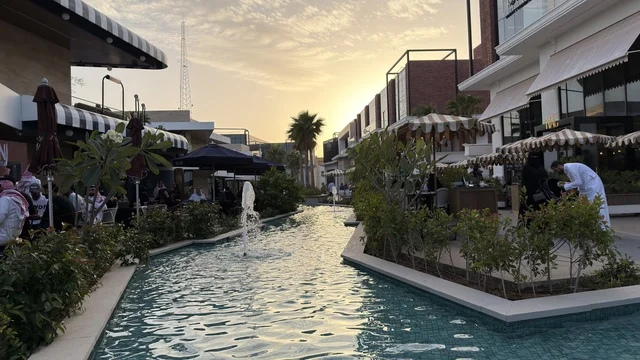مجمع تجاري حديث مع قناة مائية ونافورة عند الغروب