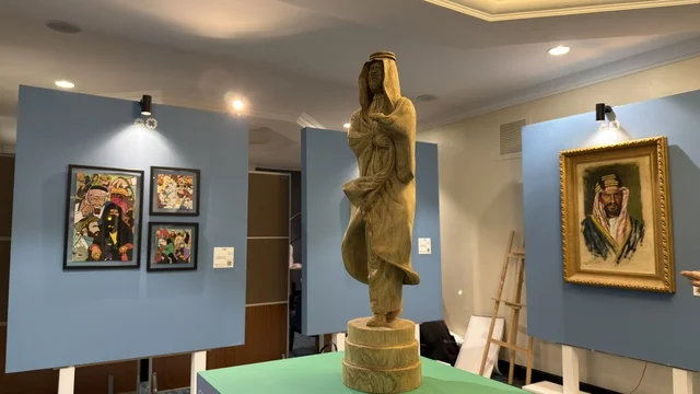 تمثال خشبي ولوحات فنية في معرض تراث سعودي