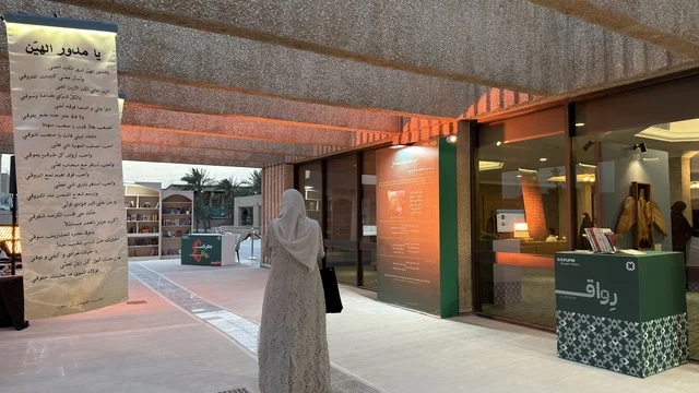 امرأة في معرض ثقافي مع لوحات الخط العربي