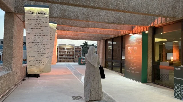 امرأة تسير في معرض ثقافي خارجي للشعر العربي