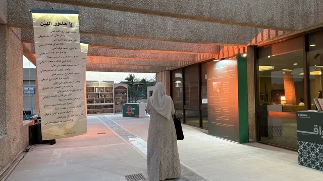 امرأة عربية تمشي في معرض ثقافي خارجي