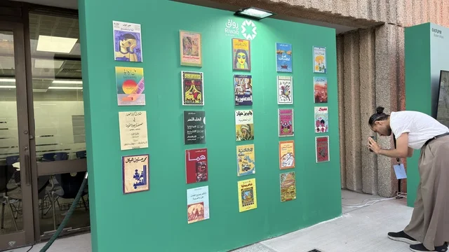 رجل يصور جدار عرض كتب عربية في الخارج