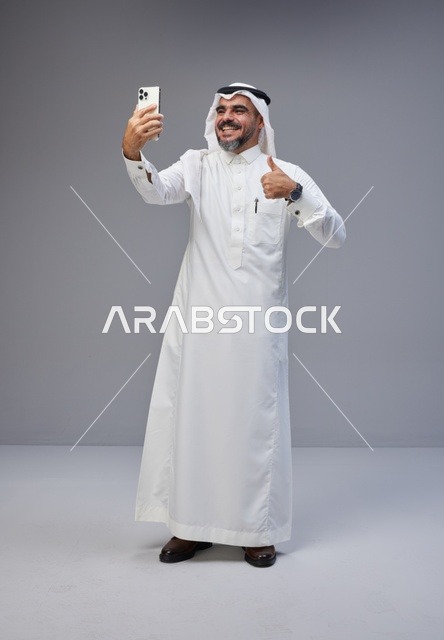 رجل سعودي بالزي التقليدي يلتقط سيلفي بالهاتف