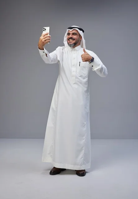 رجل سعودي بالزي التقليدي يلتقط سيلفي بالهاتف